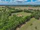 Scenic aerial shot of the home amidst rolling green pastures and scattered trees, creating a picturesque landscape at 35657 Ashley Ln, Dade City, FL 33523
