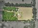 Aerial view of acreage and fenced-in area, showing barn and outbuildings surrounded by trees at 35657 Ashley Ln, Dade City, FL 33523