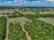 Acreage aerial view with a long driveway leading to a house surrounded by trees and fields at 35657 Ashley Ln, Dade City, FL 33523