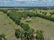 Vast property showcases a cozy home nestled amongst mature trees and green fields, offering privacy and space at 35657 Ashley Ln, Dade City, FL 33523