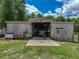 Barn with a boat inside, a concrete entrance, and wooden sides under a blue sky with green grass at 35657 Ashley Ln, Dade City, FL 33523