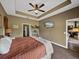 Comfortable bedroom featuring a ceiling fan, TV, and a view into the en-suite bathroom at 35657 Ashley Ln, Dade City, FL 33523