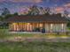 Charming wooden home at dusk with a spacious front porch and seating area at 35657 Ashley Ln, Dade City, FL 33523