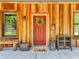 Charming wood home featuring a red door adorned with a wreath, a small window, and rustic decor at 35657 Ashley Ln, Dade City, FL 33523