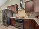 Kitchen featuring stainless steel appliances, granite countertops, dark wooden cabinets, and a stylish range hood at 35657 Ashley Ln, Dade City, FL 33523