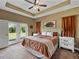 Serene main bedroom with tray ceilings, a ceiling fan, French doors leading to a yard, and an en-suite bathroom at 35657 Ashley Ln, Dade City, FL 33523