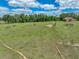 Expansive grassy acreage with mature trees, outbuildings, and a charming house in the background at 35657 Ashley Ln, Dade City, FL 33523