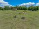 Aerial view of a vast grassy field with trees, buildings, and clear skies at 35657 Ashley Ln, Dade City, FL 33523