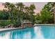 Inviting pool features a rock waterfall and is surrounded by lush landscaping and tropical palm trees at 4106 Queller Way, Tampa, FL 33618