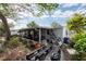 Rear view showing the screened porch and neglected yard with overgrown plants and debris at 4111 W Marietta St, Tampa, FL 33616