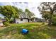 Exterior shot of damaged home with overgrown lawn and debris-filled front yard at 4111 W Marietta St, Tampa, FL 33616