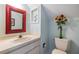 Bright half bath features a red framed mirror, fresh bouquet of flowers, and neutral fixtures at 486 Lakeview Dr # 54, Palm Harbor, FL 34683