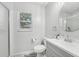 Bright bathroom featuring a white vanity, modern sink, round mirror, toilet and tiled shower with a window at 5302 Aloha Seed Dr, Seffner, FL 33584