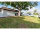 A view of the house exterior with sliding glass doors, large tree and a grassy backyard at 8721 Bay Crest Ln, Tampa, FL 33615