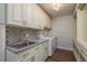 This laundry room features a sleek stainless steel sink, ample cabinetry, granite countertops, and stylish backsplash at 8721 Bay Crest Ln, Tampa, FL 33615