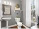 Cozy half bath features a pedestal sink, toilet, wood floors, and a decorative wreath and mirror at 9534 W Park Village Dr, Tampa, FL 33626