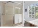 Bright bathroom with a glass enclosed shower with a mounted shower head, white towels and tile, and a large window at 9534 W Park Village Dr, Tampa, FL 33626