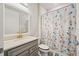 Bathroom with gray vanity, neutral countertop, stylish gold faucet, and decorative floral shower curtain at 10303 Malvasia Ave, Riverview, FL 33578