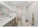 Bright bathroom with double vanity, gray cabinets, and walk-in shower with decorative curtain at 10303 Malvasia Ave, Riverview, FL 33578