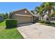 Inviting home featuring a lush lawn, mature trees, and a two-car garage at 11506 Mansfield Point Dr, Riverview, FL 33569