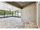 A sunlit screened-in patio has neutral stone flooring and ceiling fan at 11506 Mansfield Point Dr, Riverview, FL 33569