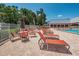 Relaxing poolside area featuring lounge chairs, tables, umbrellas, and a well-maintained deck area at 11800 Ivywood Pl, New Port Richey, FL 34654