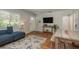 Bright living room with a comfortable blue sofa, wood-look floors, and a mounted television at 1253 Union St, Clearwater, FL 33755