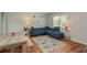 Inviting living room features wood flooring, a cozy blue sofa, and large windows for plenty of natural light at 1253 Union St, Clearwater, FL 33755