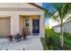 Charming front porch featuring a blue door, a chair, and lovely landscaping including a small palm tree at 12775 Maple Bonsai Dr, Riverview, FL 33579