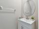 Modern half bathroom with a white vanity, oval mirror, and neutral walls at 12775 Maple Bonsai Dr, Riverview, FL 33579