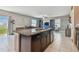 Large kitchen island with sink and dark cabinets, with open view into living room and dining area at 12775 Maple Bonsai Dr, Riverview, FL 33579