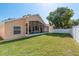 Spacious backyard with a screened lanai, a well-maintained lawn, and a white fence at 1285 Salt Lake Dr, Tarpon Springs, FL 34689