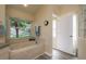 Bright bathroom featuring a soaking tub, tile surround and a view to the exterior at 1285 Salt Lake Dr, Tarpon Springs, FL 34689