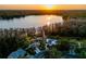 Gorgeous aerial view featuring a lake reflecting the sunset, a pool, residences, and lush green landscape at 16819 Stanza Ct, Tampa, FL 33624