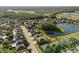Aerial view of a community with houses surrounding a lake with green trees at 17917 Machair Ln, Land O Lakes, FL 34638