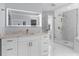 Elegant bathroom featuring white marble floors, a vanity with a lighted mirror, and a glass shower at 17917 Machair Ln, Land O Lakes, FL 34638