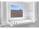 Elegant bathroom featuring a soaking tub with marble surround and natural light at 17917 Machair Ln, Land O Lakes, FL 34638