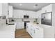 Well-lit kitchen boasts white cabinets, stainless steel appliances, an island, and wood-look flooring at 17917 Machair Ln, Land O Lakes, FL 34638