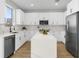 Open-concept kitchen features white cabinets, stainless appliances, island with marble countertop, and wood floors at 17917 Machair Ln, Land O Lakes, FL 34638