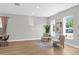 Bright, minimalist living room with wood floors, accent chairs, and large windows with a view at 17917 Machair Ln, Land O Lakes, FL 34638
