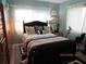 Bedroom with black, queen-sized bed and decorative pillows, lit by lamps and natural light from two windows at 2555 Royal Pines Cir # A, Clearwater, FL 33763