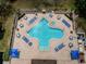 Aerial view of the community pool with lounge chairs, tables, umbrellas and manicured landscape at 2629 Timacqua Dr, Holiday, FL 34691