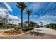 Key Vista community entrance with landscaping, palm trees, and guardhouse along paved road with blue sky background at 2629 Timacqua Dr, Holiday, FL 34691