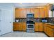 Kitchen featuring wood cabinets, granite countertops, mosaic backsplash, and stainless steel appliances at 2629 Timacqua Dr, Holiday, FL 34691