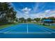 Features of this blue tennis court include a shaded seating area and well maintained green surface within the community at 2629 Timacqua Dr, Holiday, FL 34691
