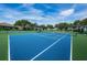 Well-maintained community tennis court with a vibrant blue surface and lush surroundings at 2629 Timacqua Dr, Holiday, FL 34691
