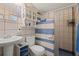 Tiled bathroom featuring a pedestal sink, toilet, and shower with blue and white accents at 2805 Olavet Ct, Valrico, FL 33596