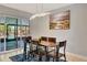 Bright dining room boasts modern light fixture, contemporary art, and glass doors at 3044 Golden Rain Dr, Sarasota, FL 34232