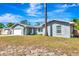 Exterior view of a home, featuring a large tree in the yard, attached garage, and freshly painted gray exterior at 3044 Golden Rain Dr, Sarasota, FL 34232