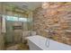 Bathroom with stone accent wall, modern fixtures, bathtub, and stone shower at 3241 Brushwood Ct, Clearwater, FL 33761